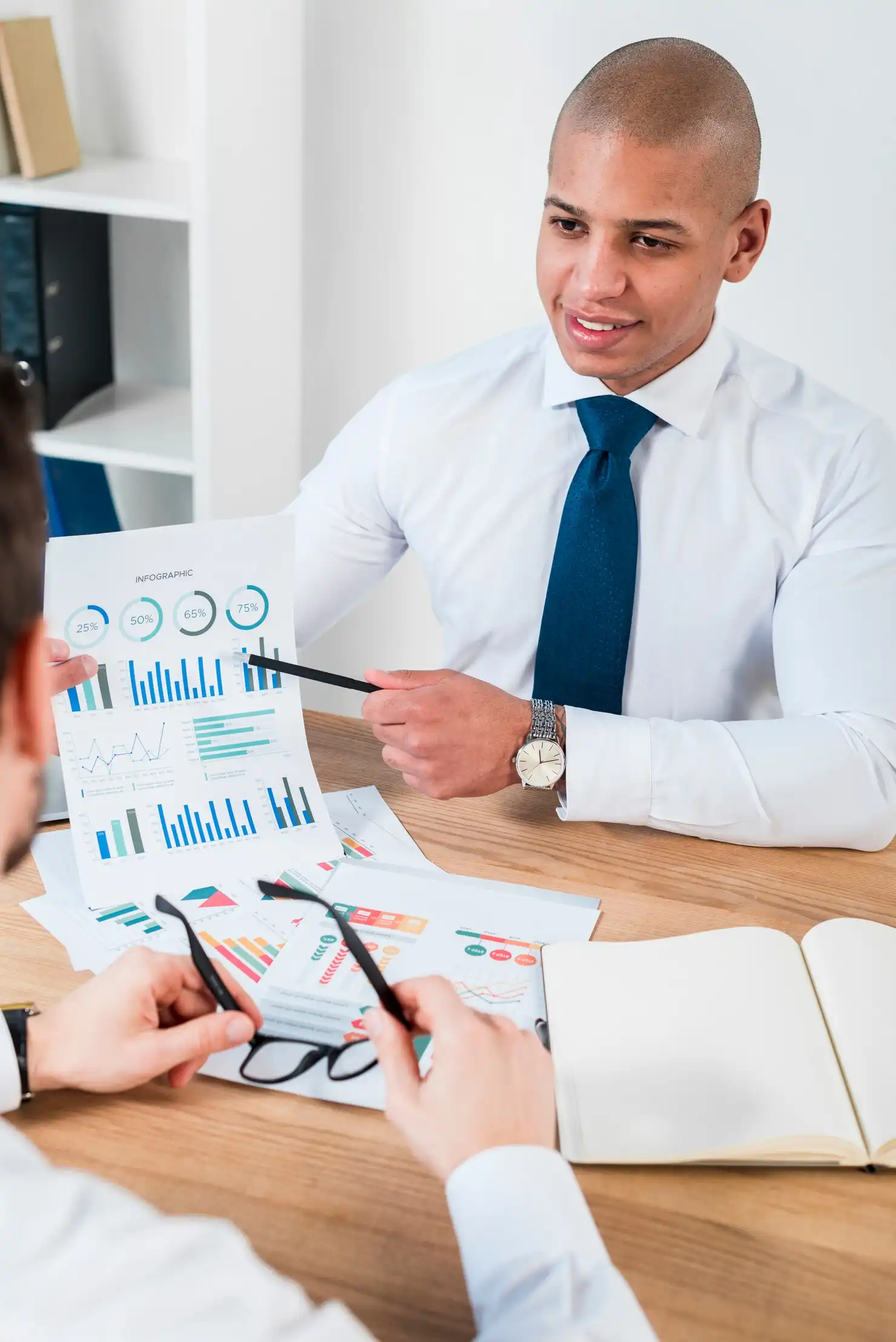 close-up-smiling-young-businessman-showing-graph-with-pencil-his-business-partner-workplace_23-2148087146